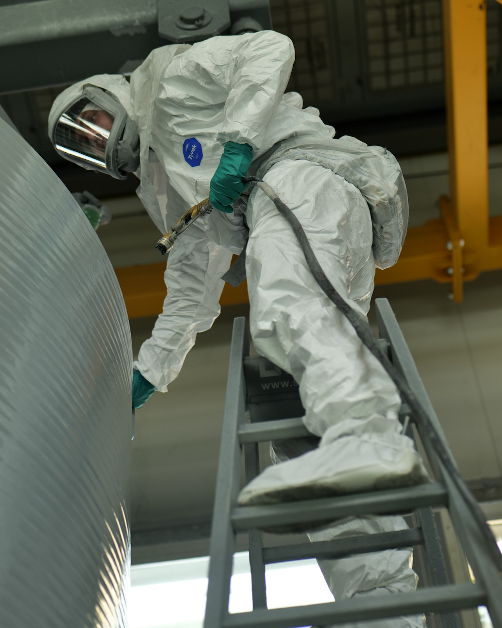 Person in Schutzanzug auf Leiter